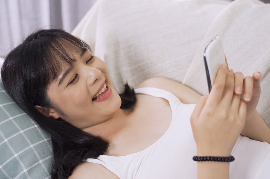 躺在沙发床上的女人阅读男友的有趣文字